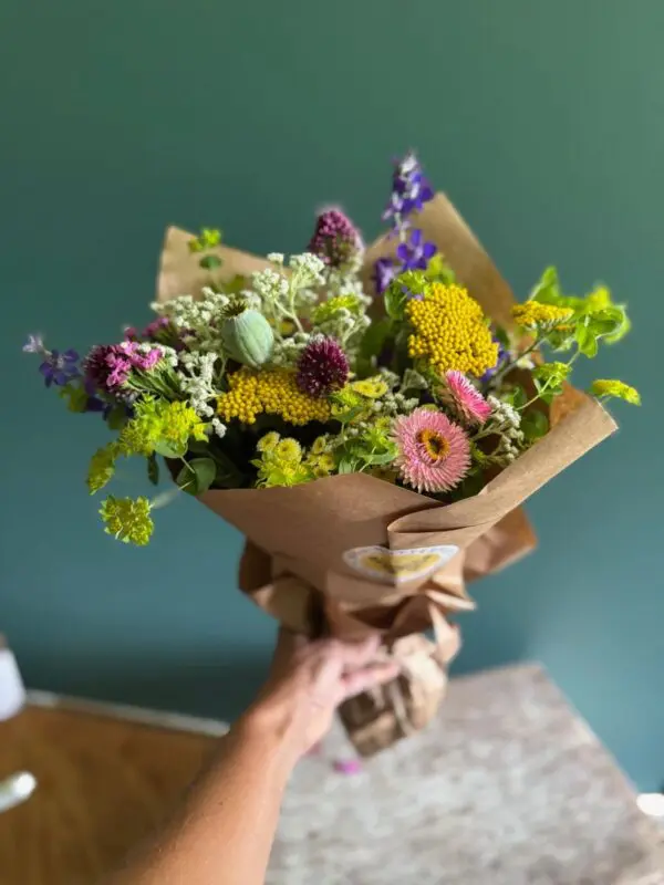 Hand holding vibrant mixed flower bouquet