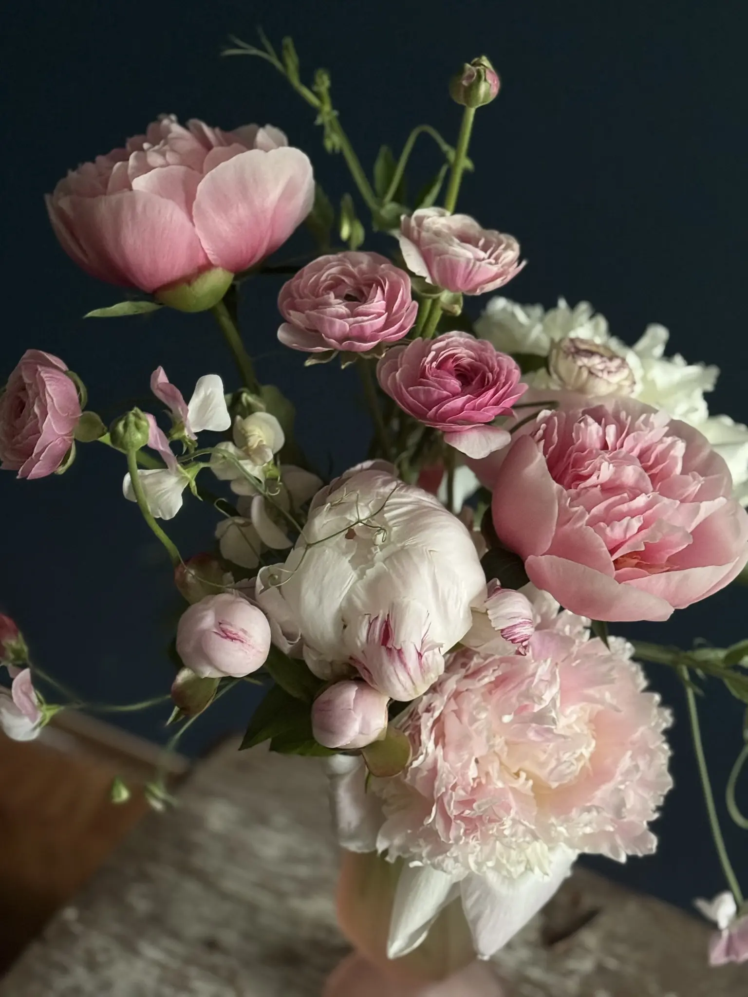 Delicate pink peonies and white flowers in a glass vase.