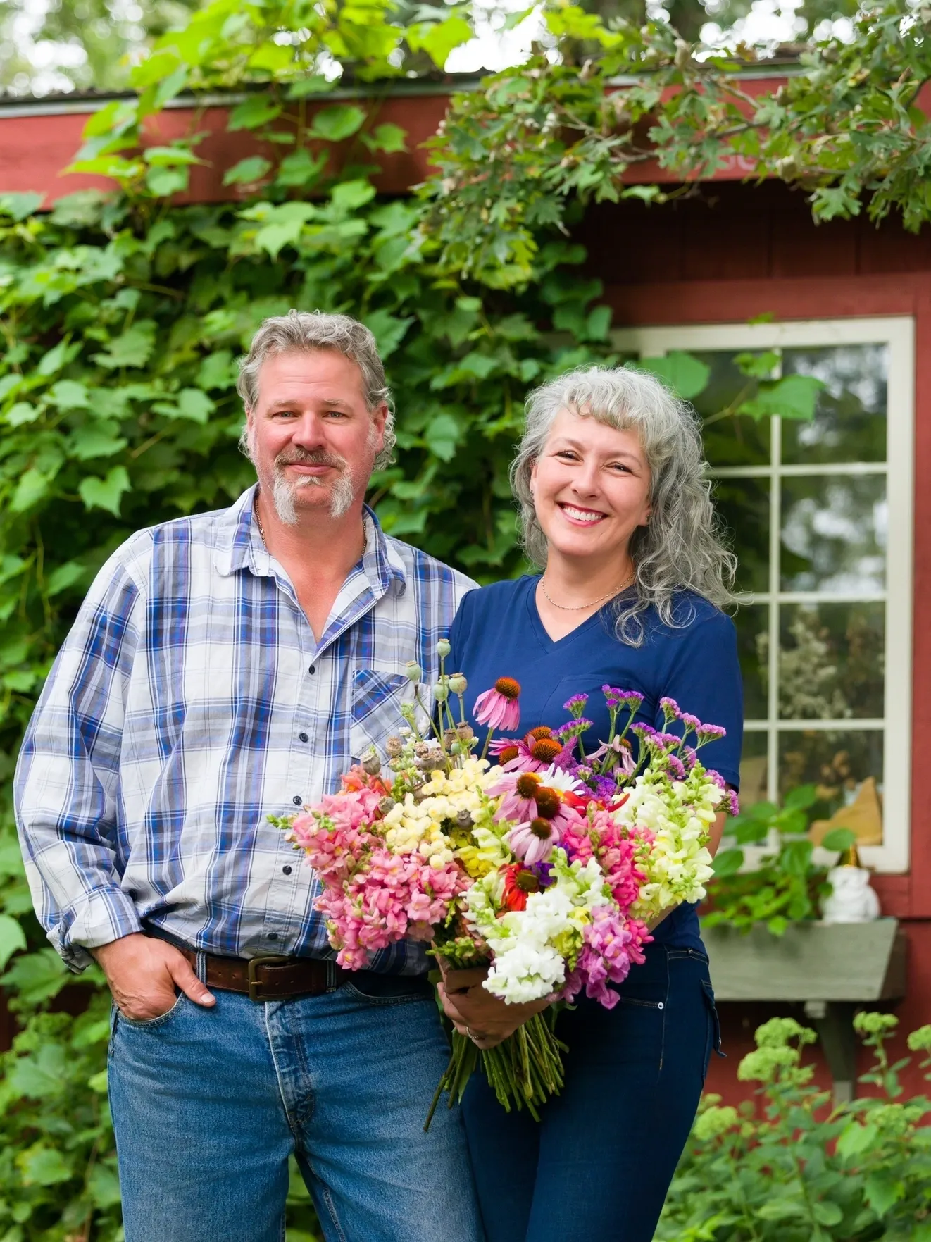 Happy couple standing outside with a large bouquet of flowers.